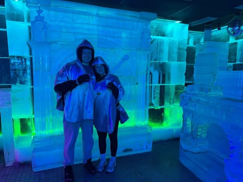 Tallulah and Thomas in winter coats in an ice bar lit in blue