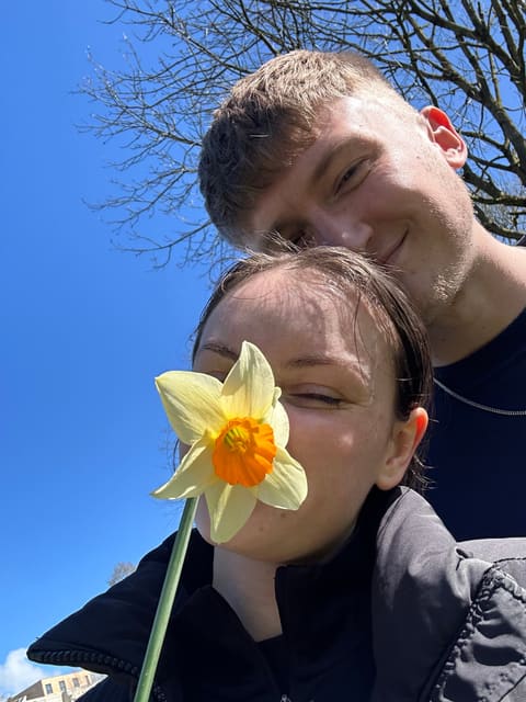 Tallulah and Thomas with a daffodil against a blue sky