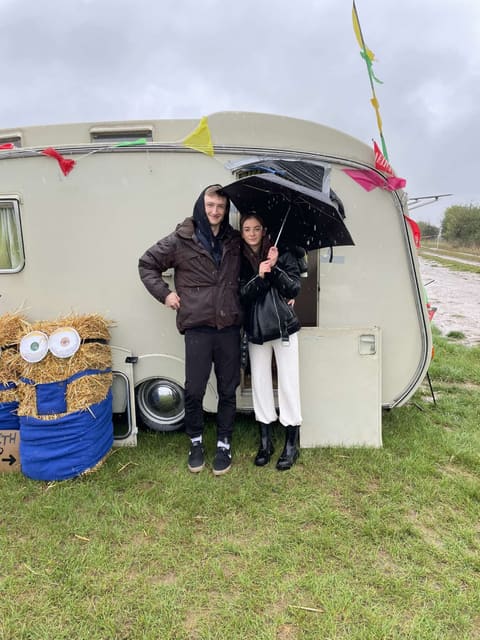 Tallulah and Thomas under an umbrella beside a vintage caravan